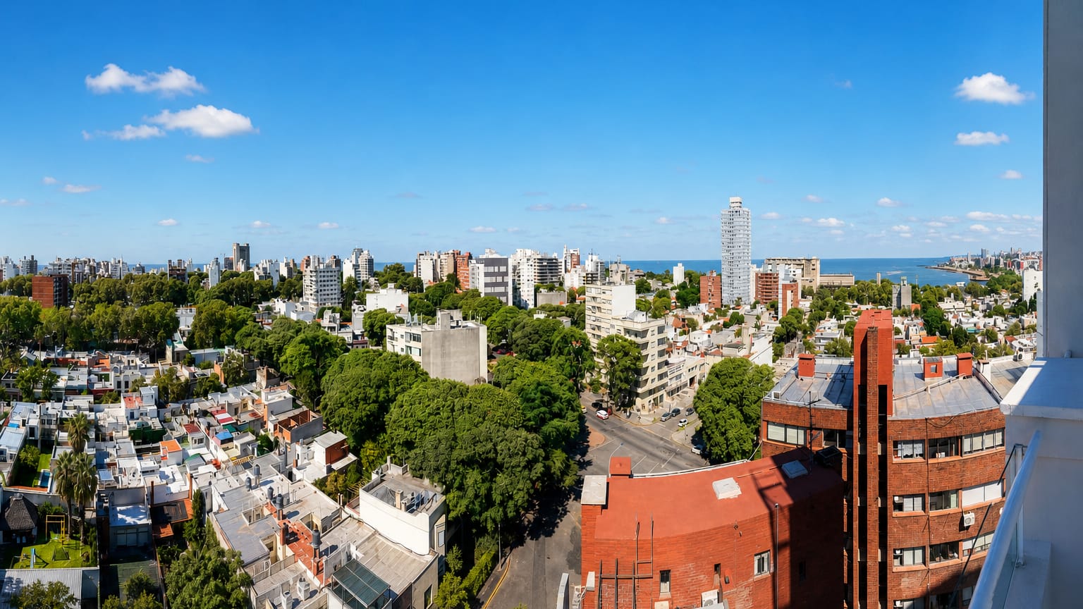 Aerial view over Montevideo's leafy residential neighbourhoods reaching the Rio de la Plata shoreline.