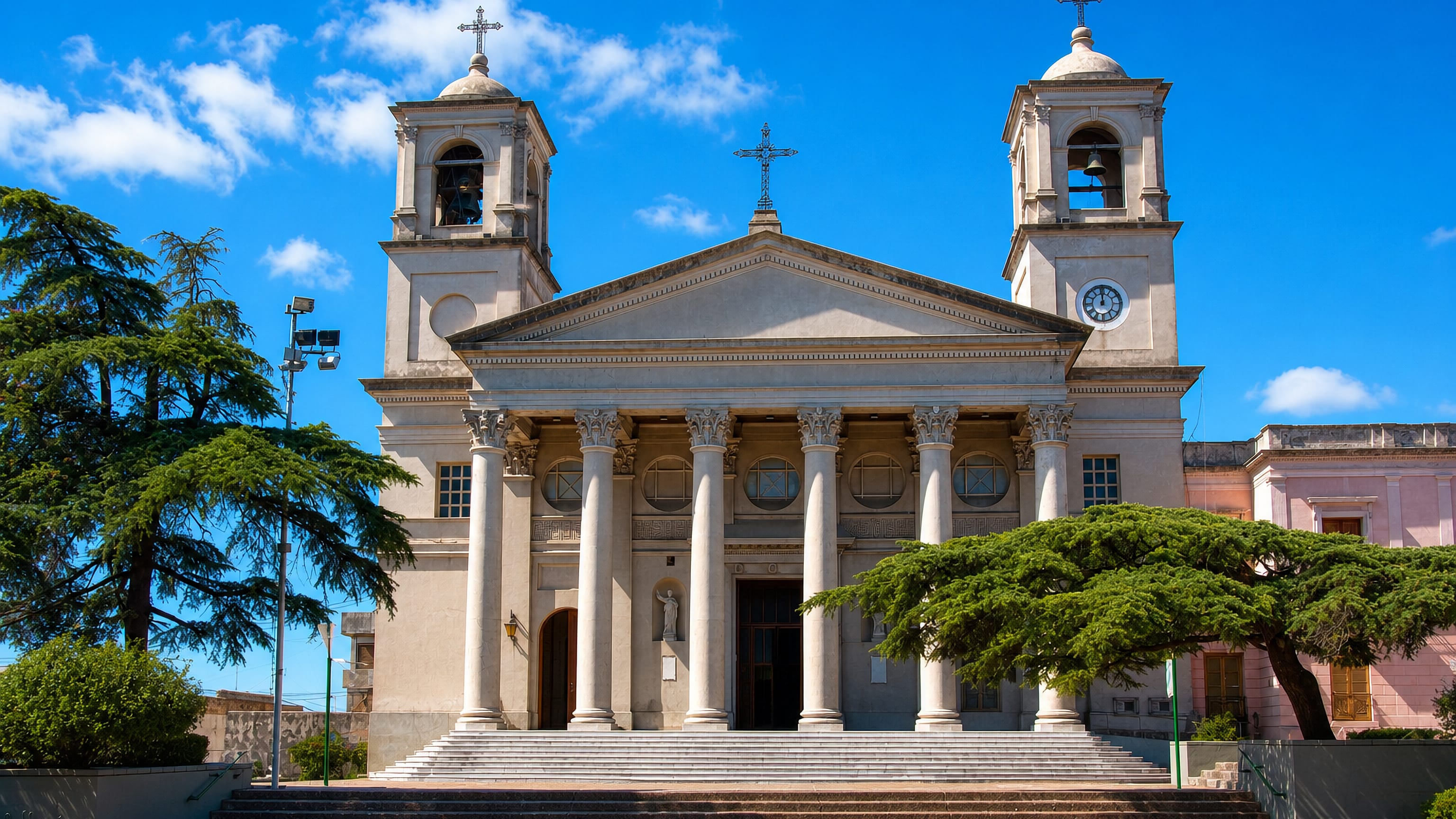 The twin-towered neoclassical basilica of Paysandú, Uruguay, fronted by wide stone steps under a blue sky.