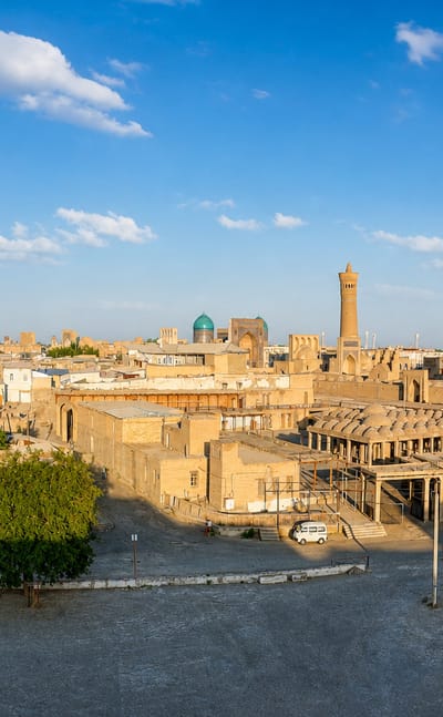 Bukhara's old town with the Kalyan Minaret and turquoise-domed mosques rising above sand-coloured houses
