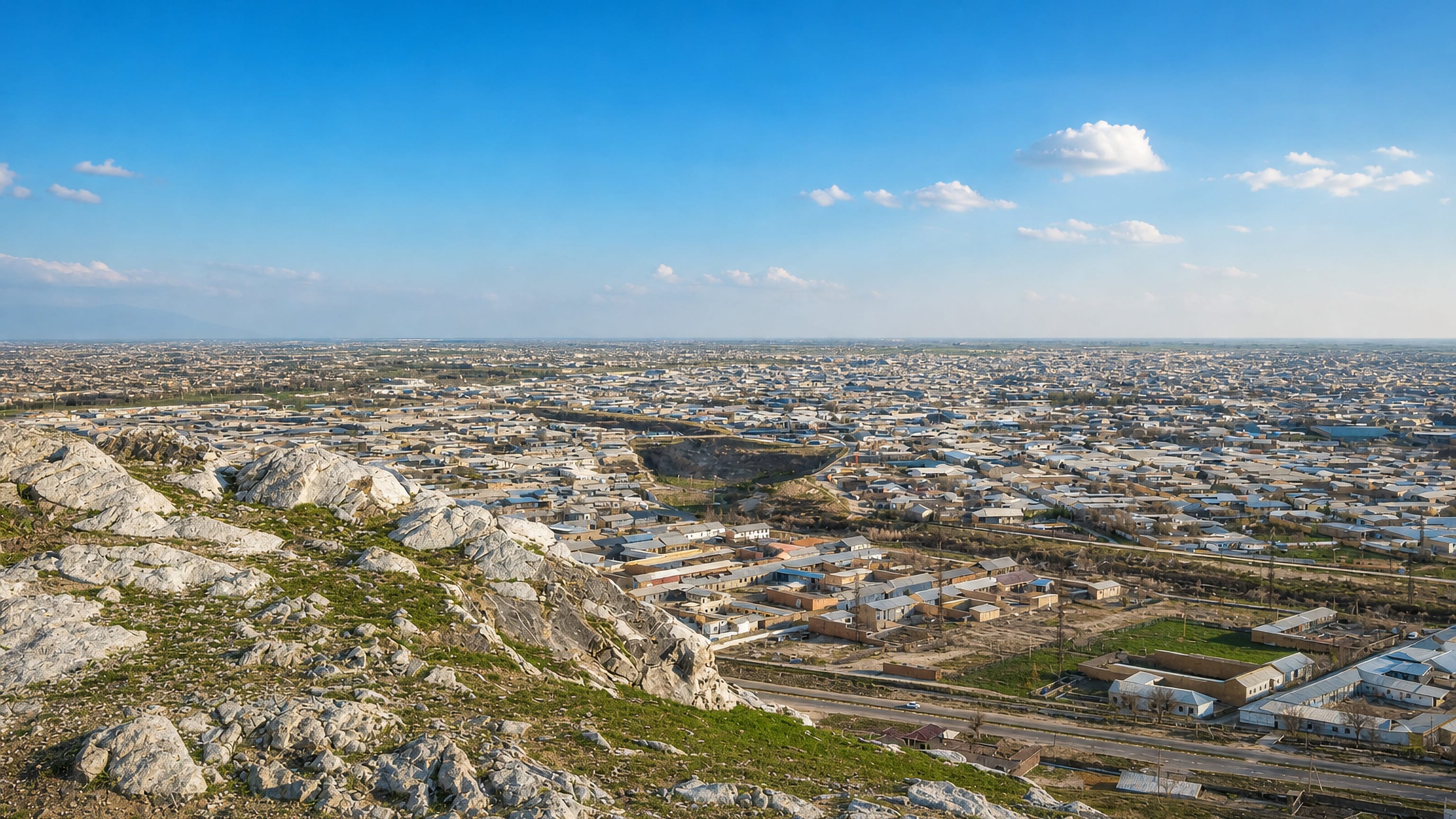 Low-rise Jizzax spreading across the plain, seen from the rocky hills above the Uzbek city.