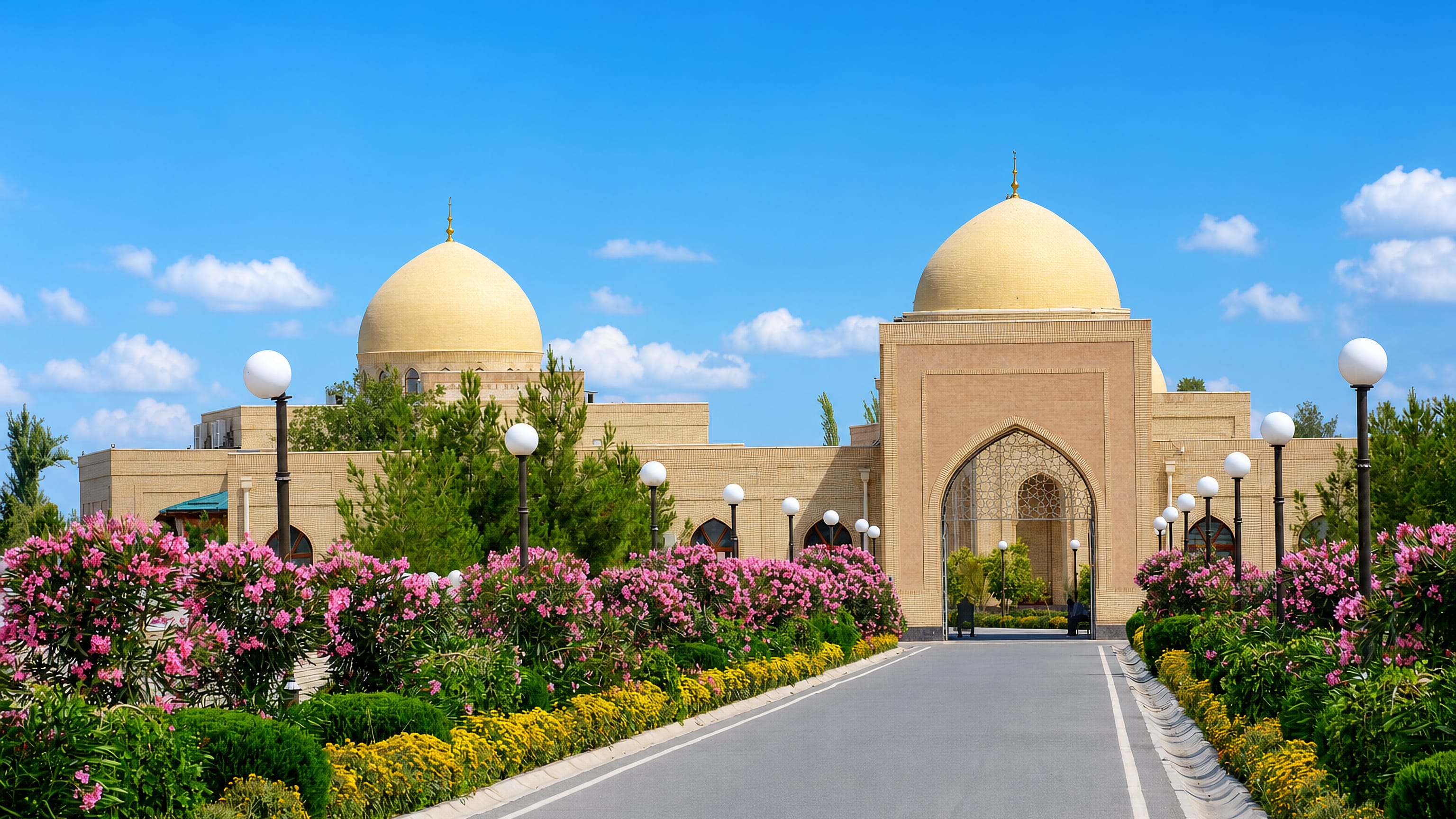 Golden-domed brick Islamic complex in Termez, Uzbekistan, approached by an oleander-lined avenue.
