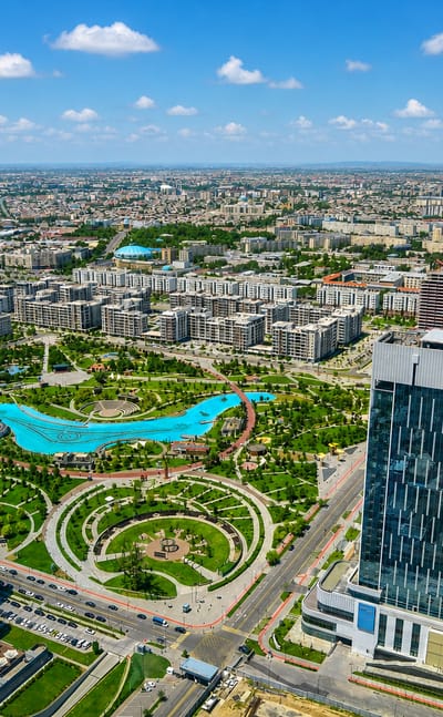 Aerial view of modern Tashkent with glass towers overlooking the landscaped lake and gardens of Tashkent City Park.