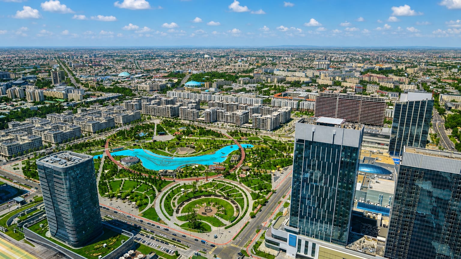 Aerial view of modern Tashkent with glass towers overlooking the landscaped lake and gardens of Tashkent City Park.