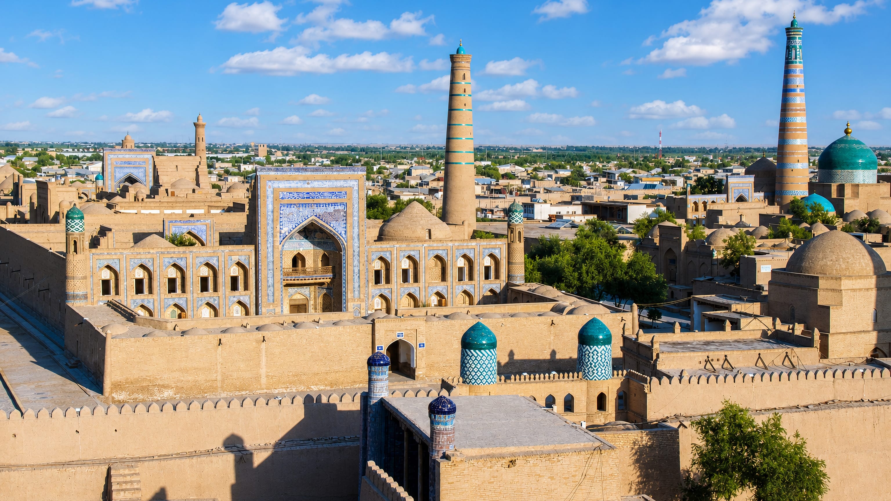 Sunlit mudbrick walls, tiled madrasa and minarets of the Itchan Kala old town in Xiva, Uzbekistan.