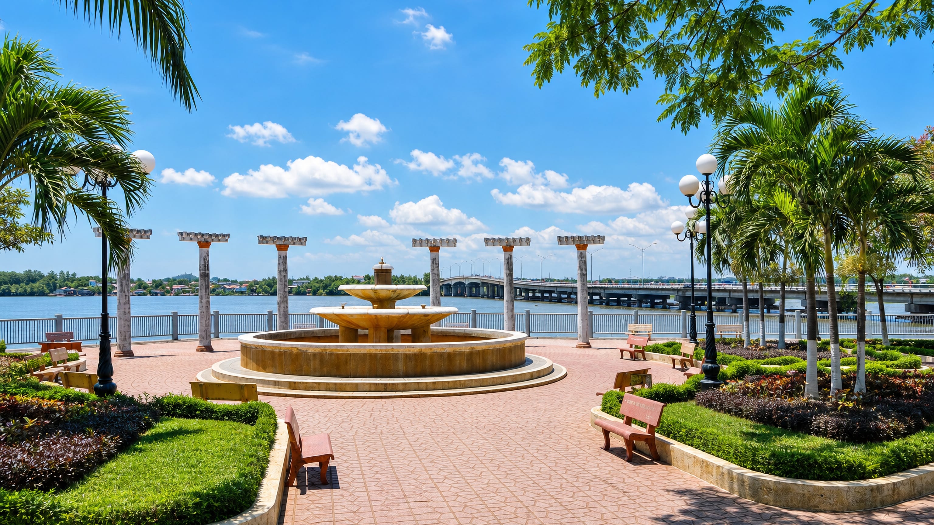 A fountain and palm-lined riverside park in Biên Hòa with the Đồng Nai bridge crossing behind.