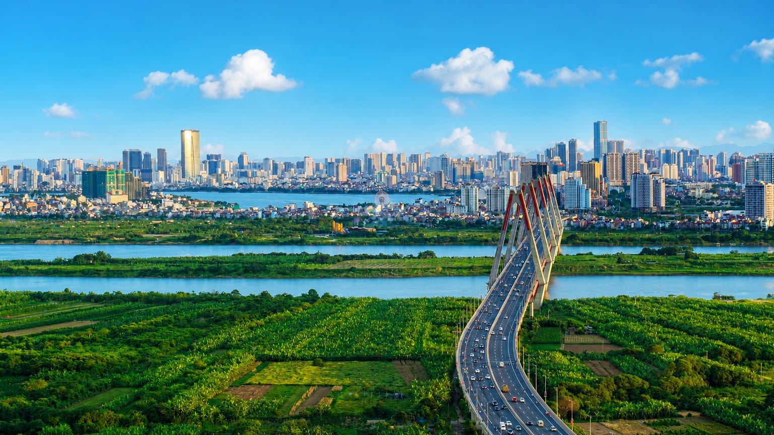 Hanoi skyline beyond the Red River floodplain, with a cable-stayed bridge and the Keangnam Landmark 72 tower on the horizon