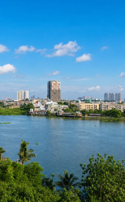 Saigon River waterfront in Binh Thanh, Ho Chi Minh City, with high-rise towers rising behind riverside greenery.