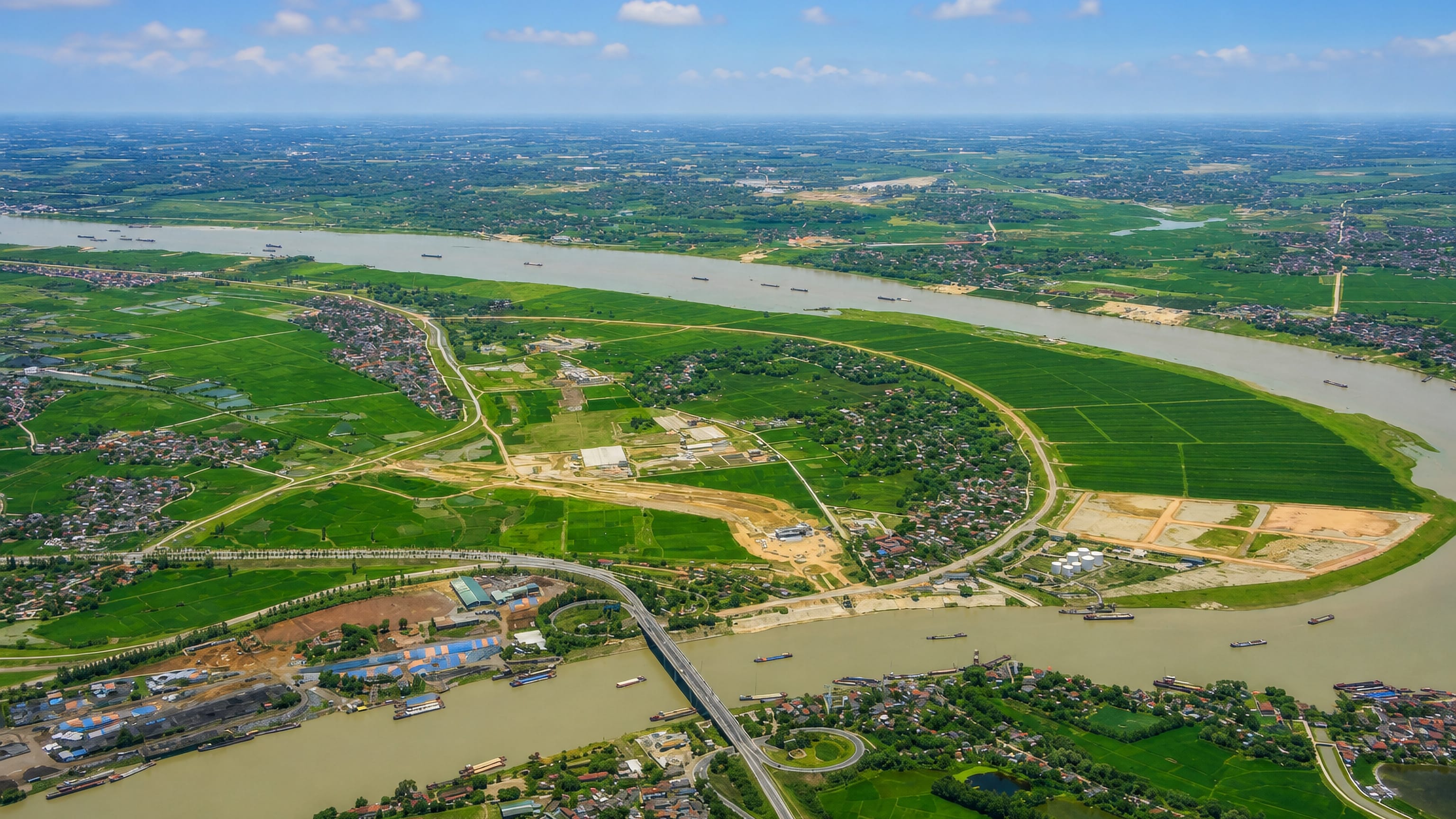Aerial view of the Red River curving past farmland and a road bridge near Viet Tri, Vietnam.