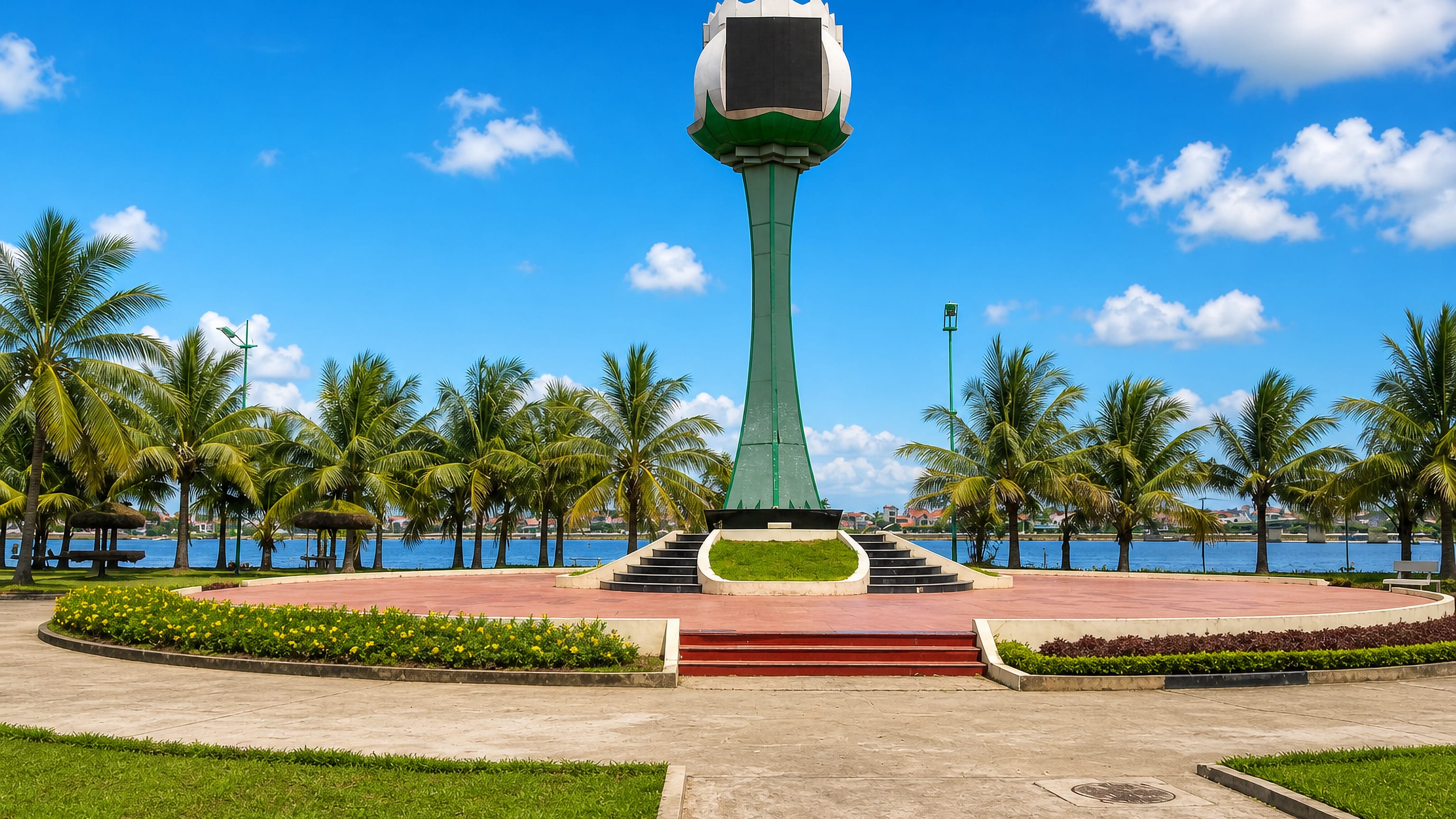 Lotus-shaped monument tower on the palm-lined riverside promenade at Đồng Hới, Vietnam.