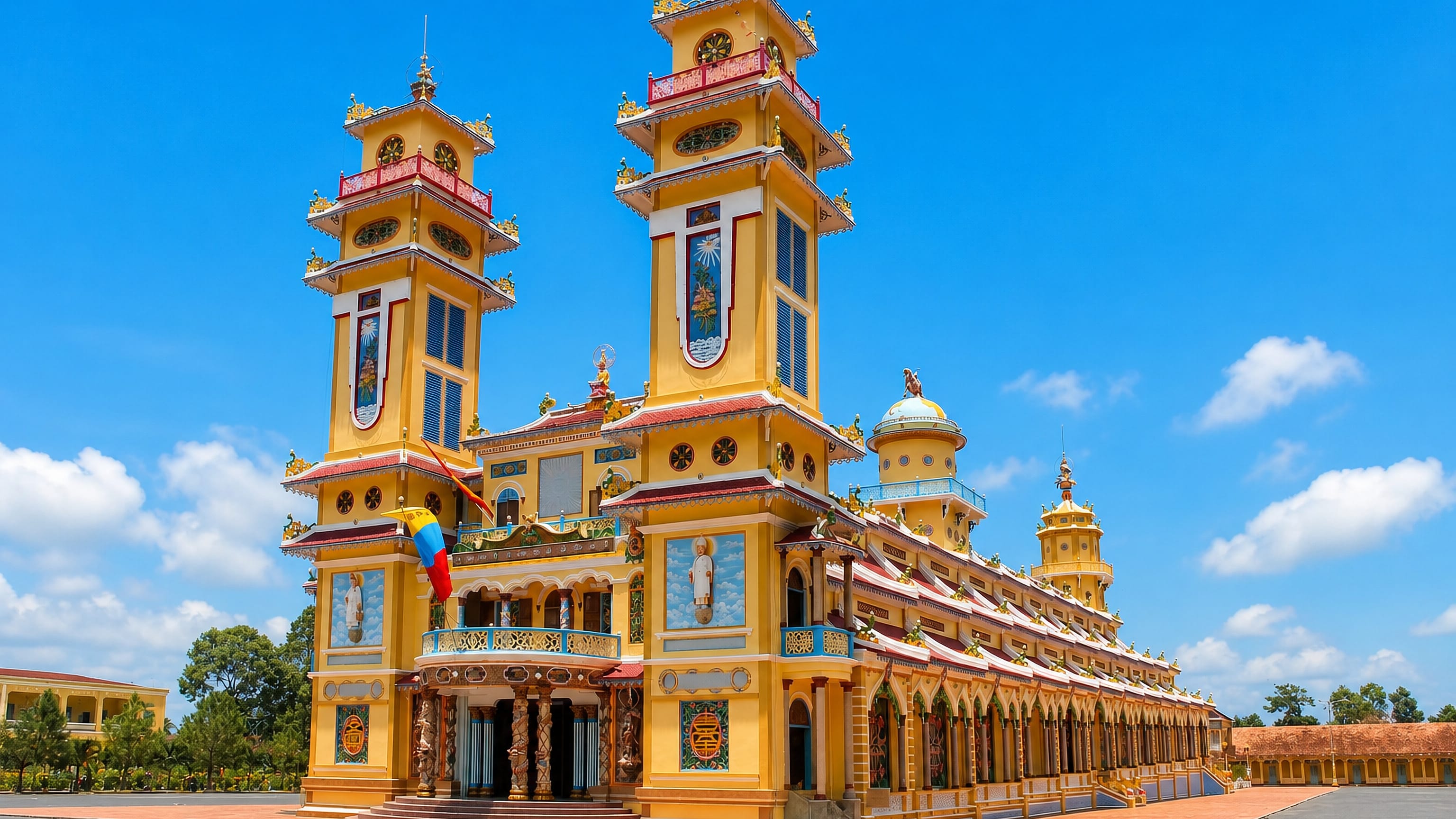 The twin-towered Cao Dai Holy See temple at Tay Ninh, Vietnam, under bright midday sky.