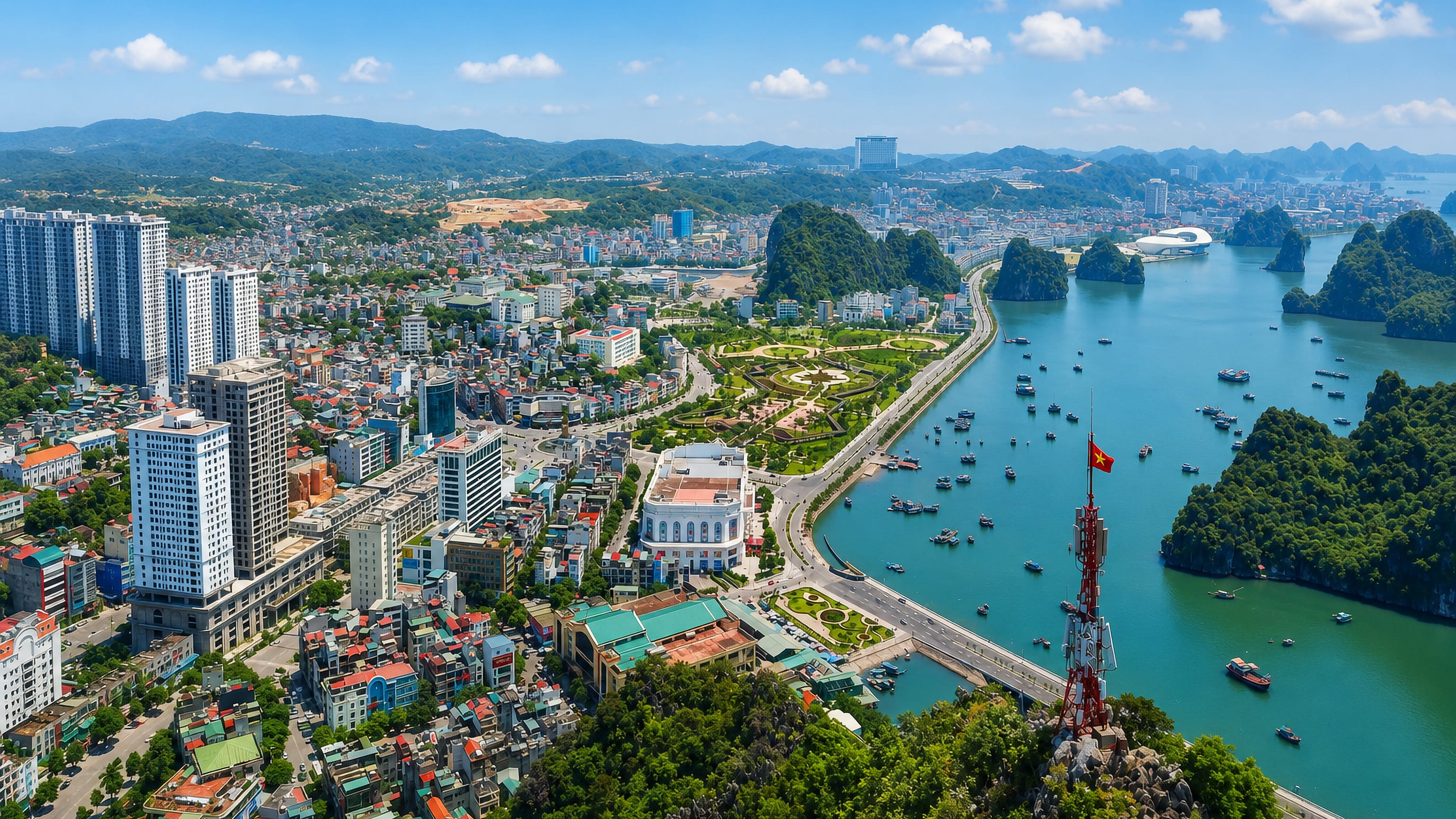 Ha Long city and its limestone karst bay seen from Bai Tho Mountain, with a Vietnamese flag on the radio tower.