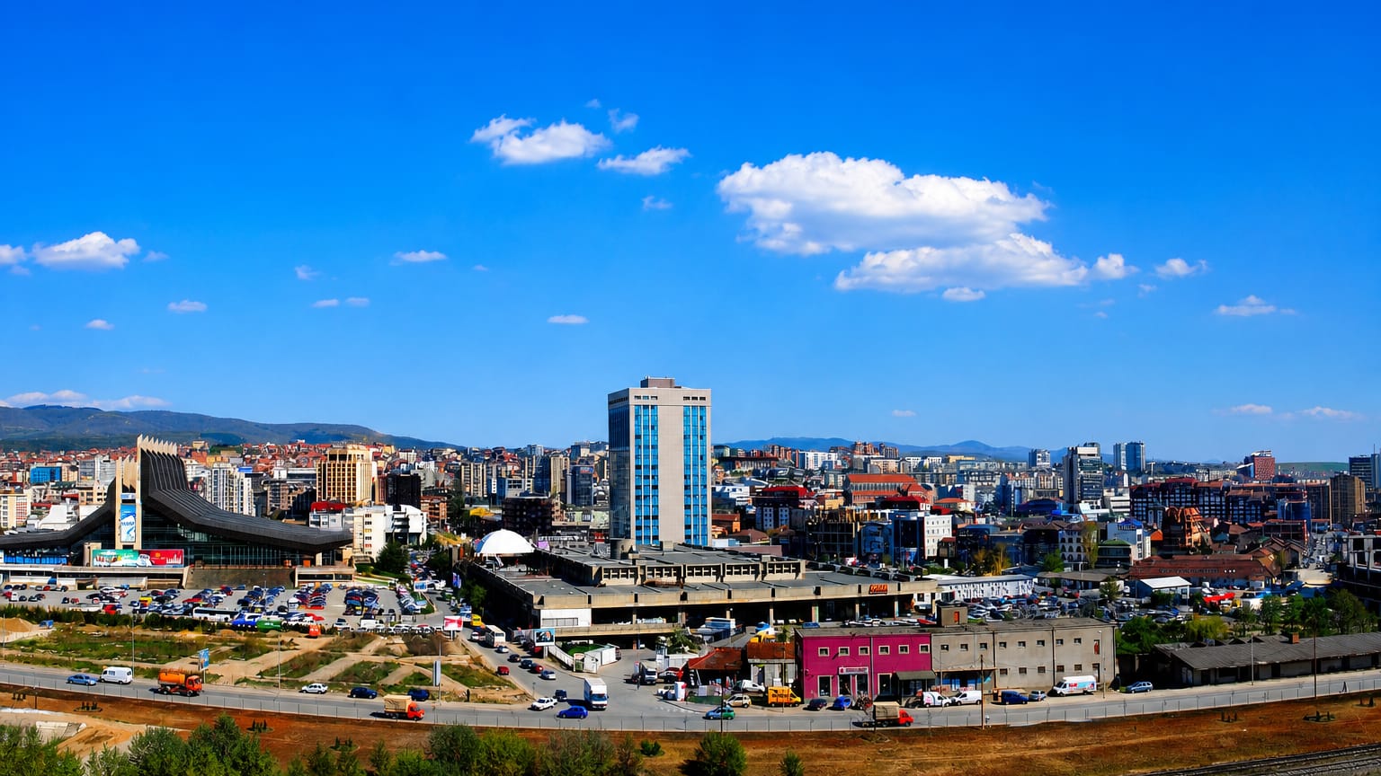Pristina skyline with the Palace of Youth and Sports and central high-rises under a blue sky.
