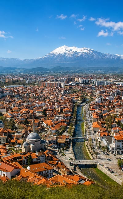 Prizren, Kosovo, red-roofed old town along the Bistrica River below the snow-capped Sharr Mountains.
