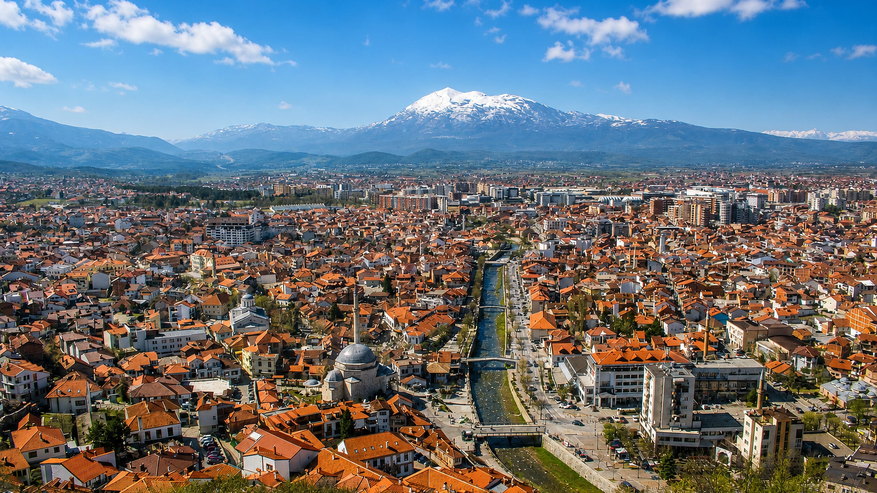 Prizren, Kosovo, red-roofed old town along the Bistrica River below the snow-capped Sharr Mountains.