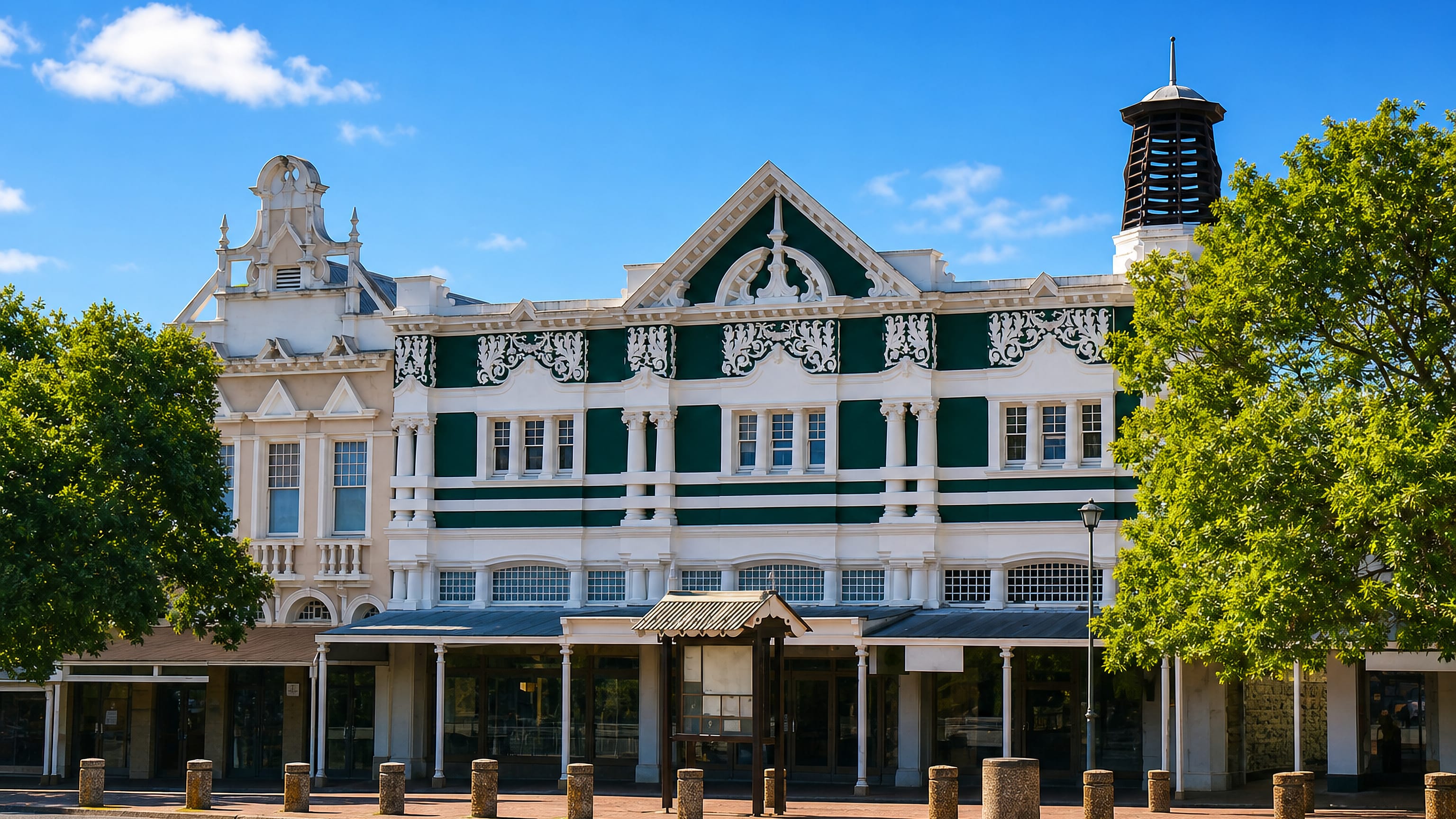 Ornate green-and-white Victorian building with a shaded verandah on the main street of Grahamstown, South Africa.