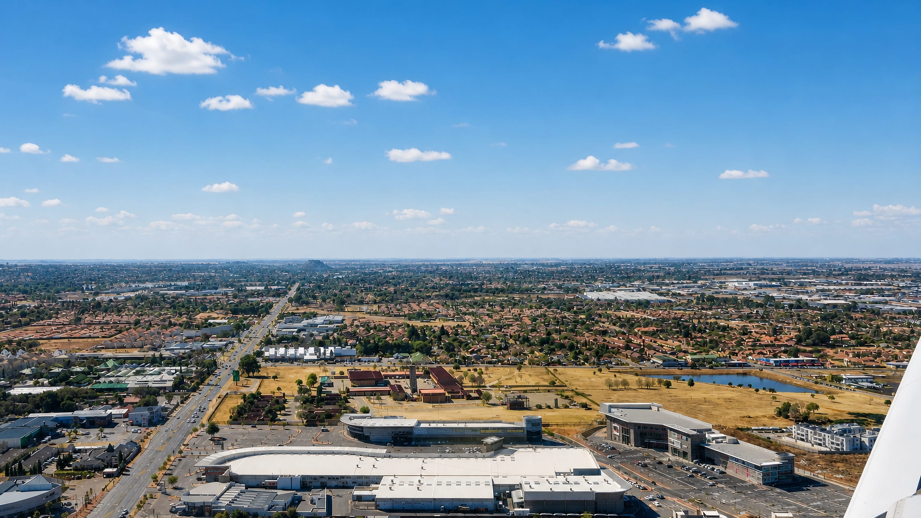 Aircraft-window view over Boksburg's suburban sprawl, shopping centres and dam on the Gauteng highveld.