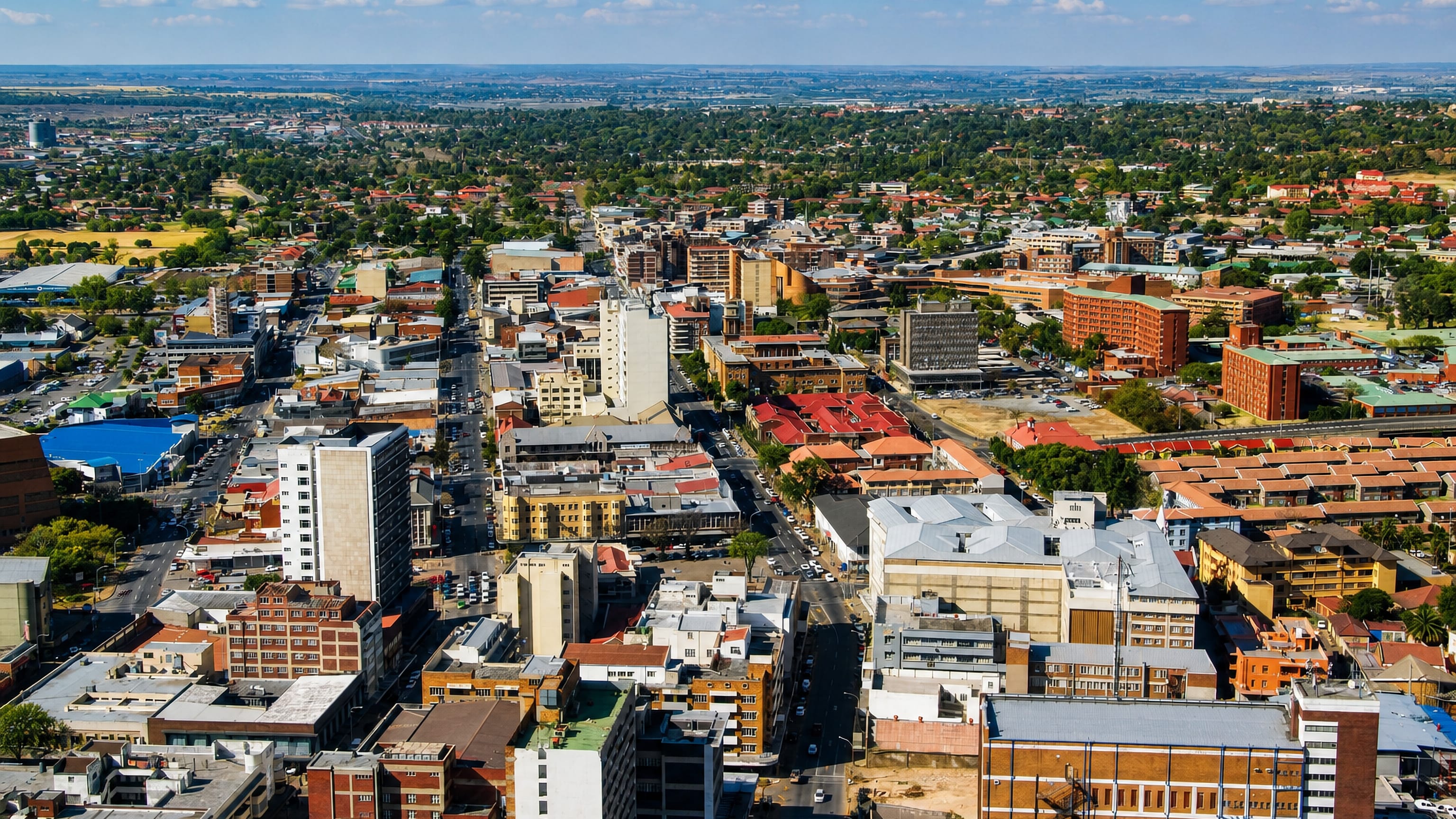 Aerial view over central Germiston, Gauteng, with mixed low-rise blocks and the Highveld horizon.