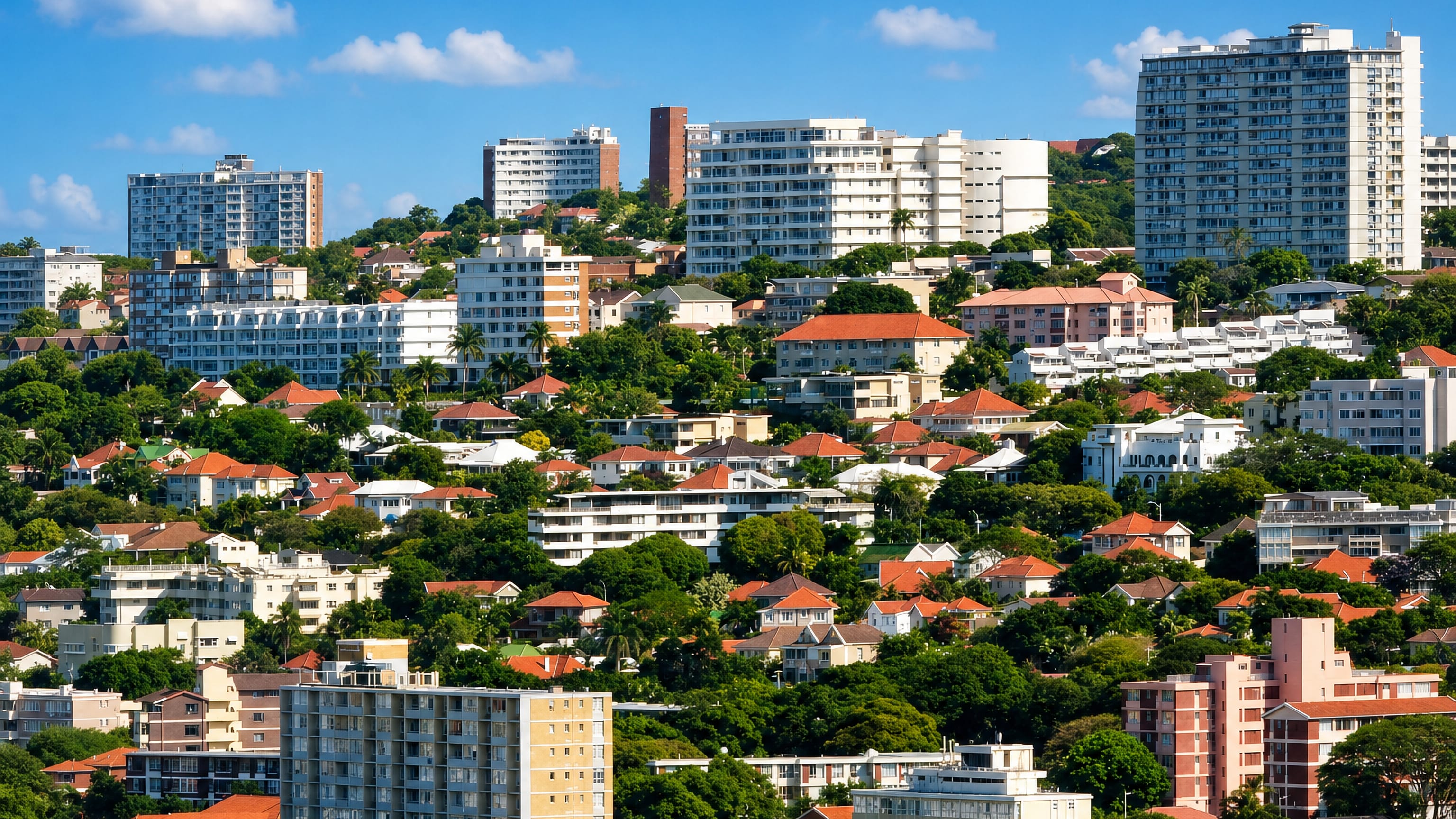 Hillside apartment blocks and red-roofed homes among subtropical trees in Essenwood, Durban.