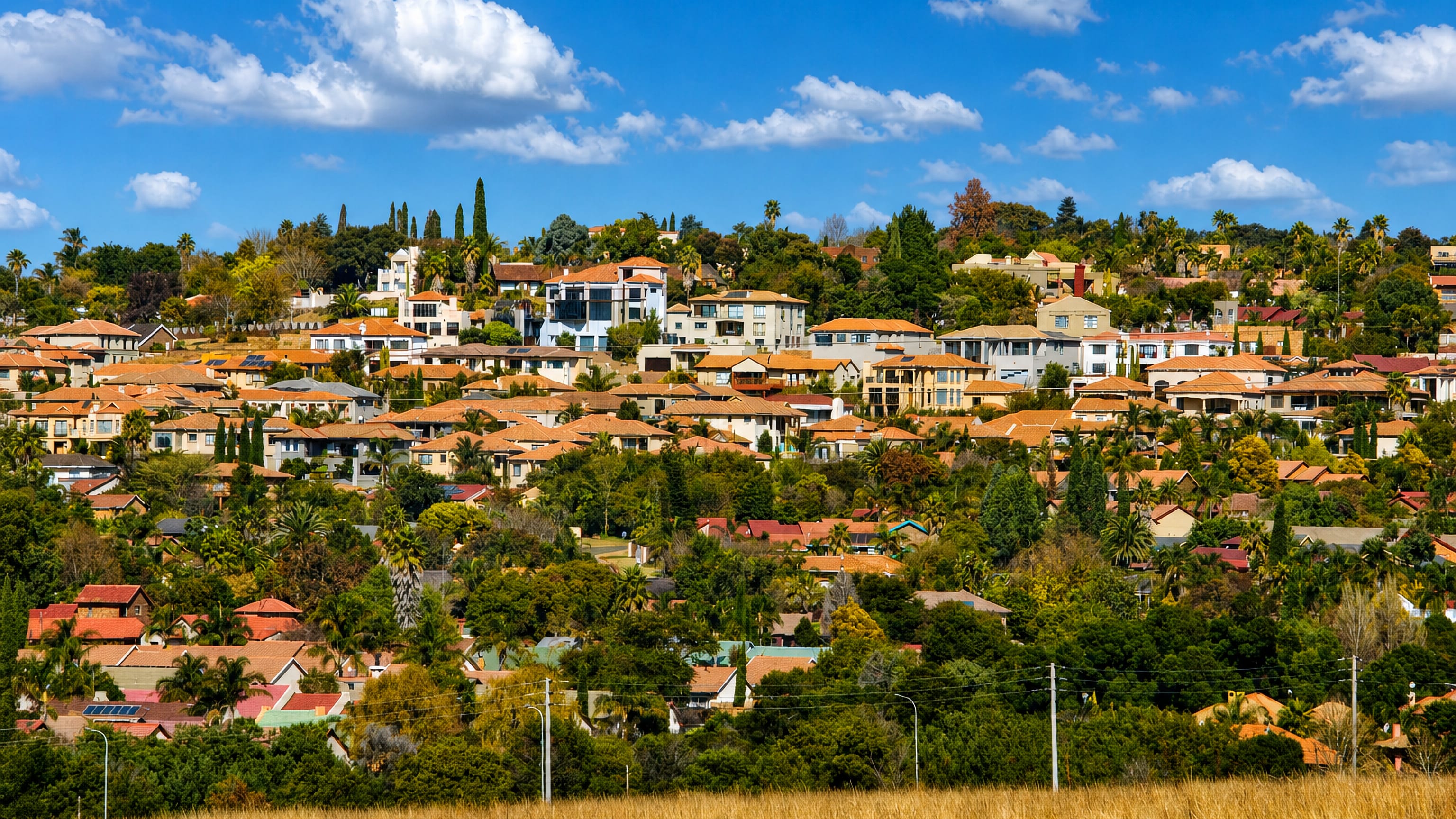 Hillside suburb of tile-roofed homes above dry highveld grass at Emalahleni, Mpumalanga, South Africa.