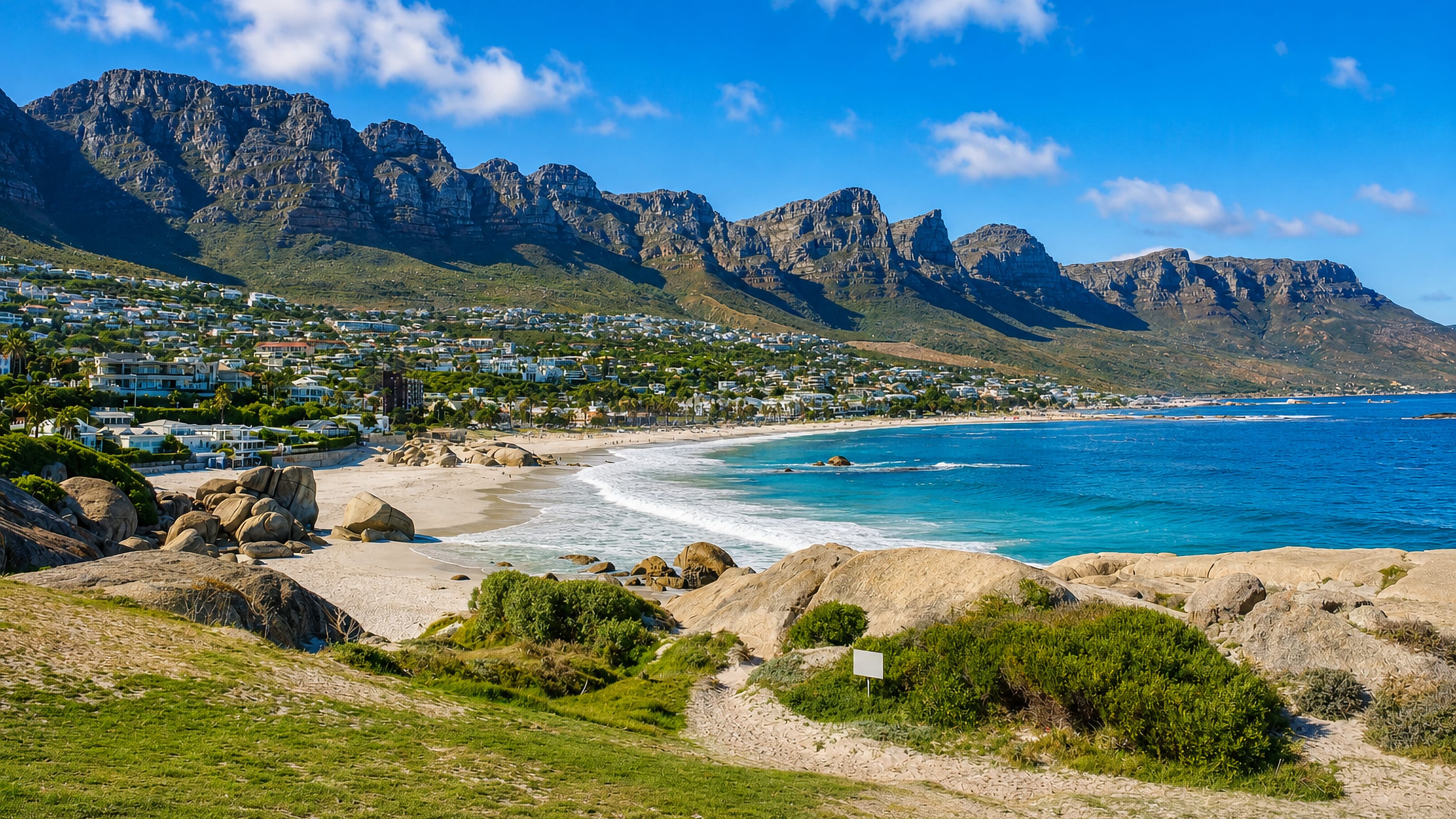 Camps Bay's white villas and boulder-strewn beach below the Twelve Apostles ridge in Cape Town.