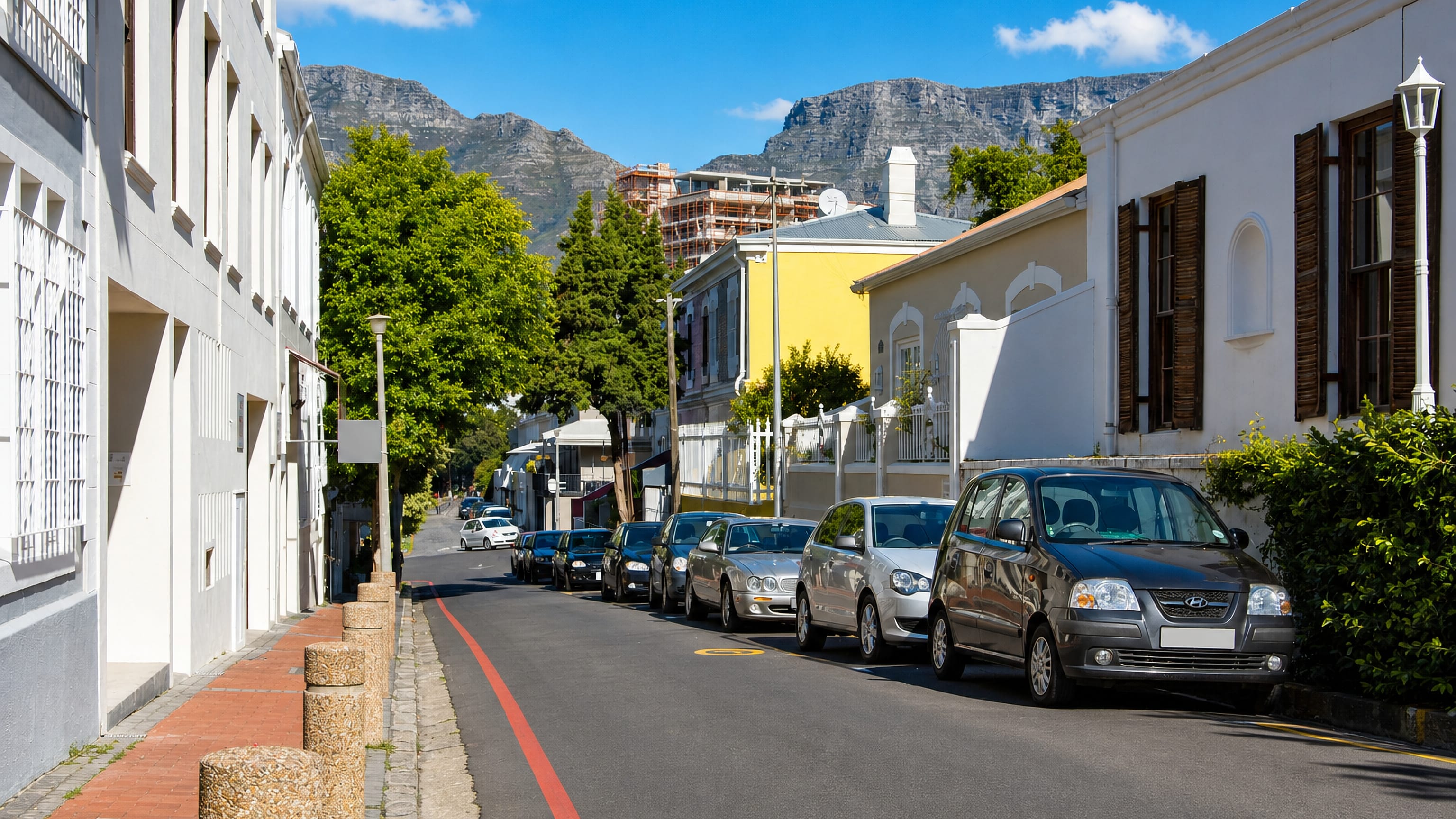 Cape Dutch cottages line a De Waterkant street in Cape Town beneath Table Mountain.