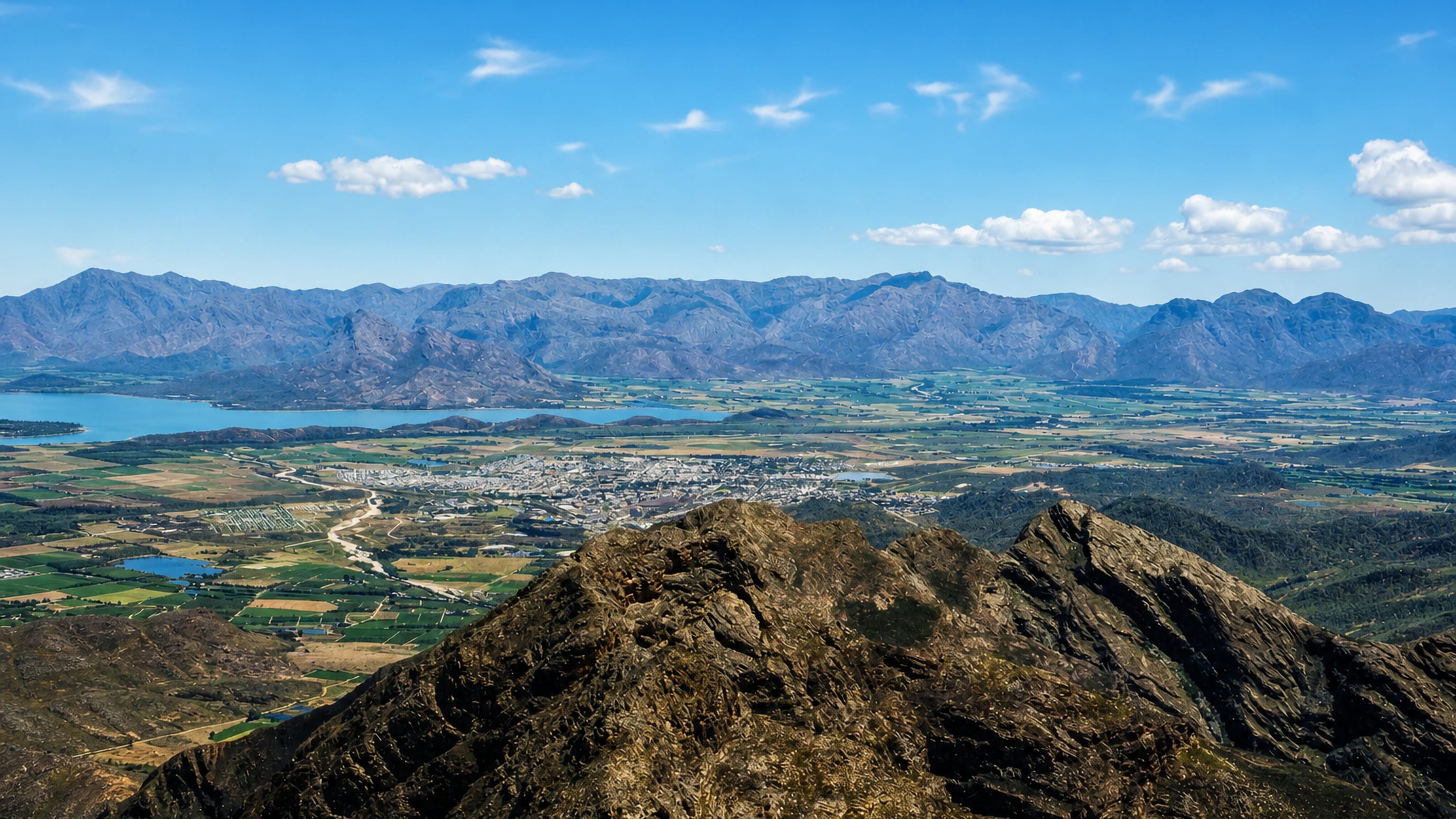 Worcester spread across Breede Valley farmland below rocky peaks, with a dam and mountain range beyond