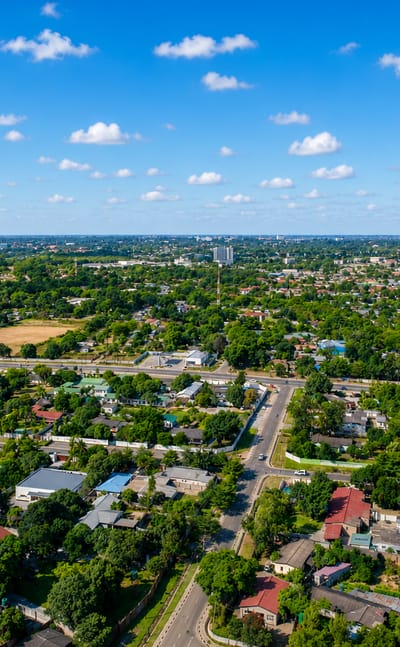 Aerial view of Lusaka's leafy low-rise suburbs and tree-lined avenues under a blue sky.